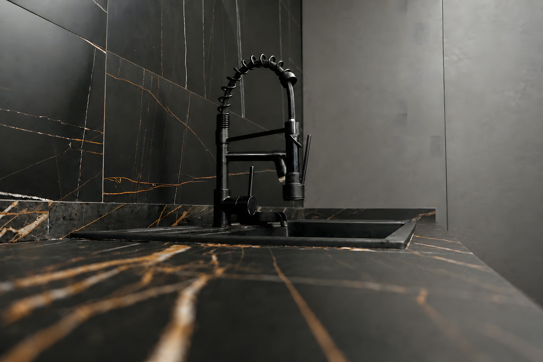 Rubinetto nero su piano cucina in marmo nero venato d'oro