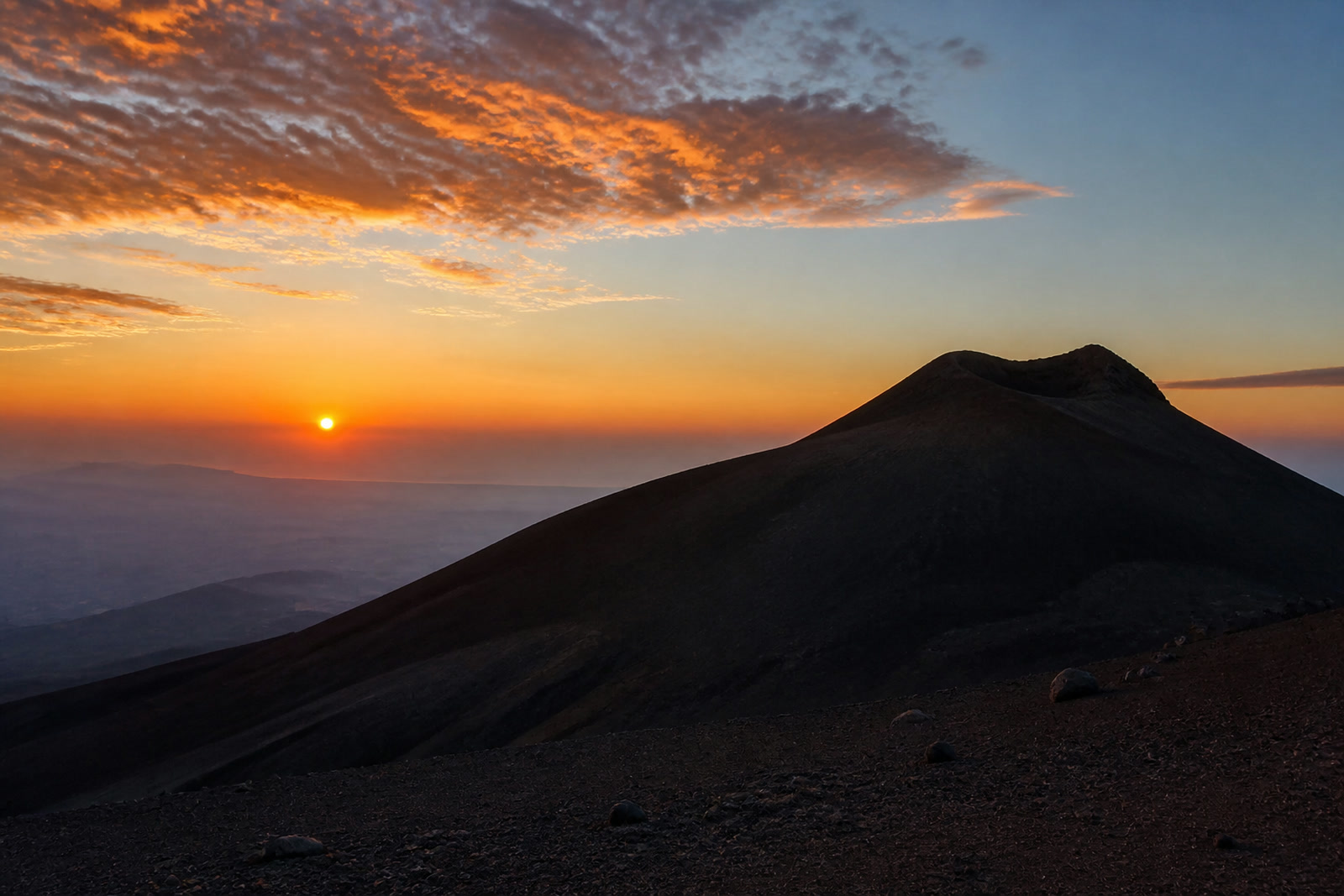 Escursionisti sul cratere al tramonto, con il vulcano alle spalle