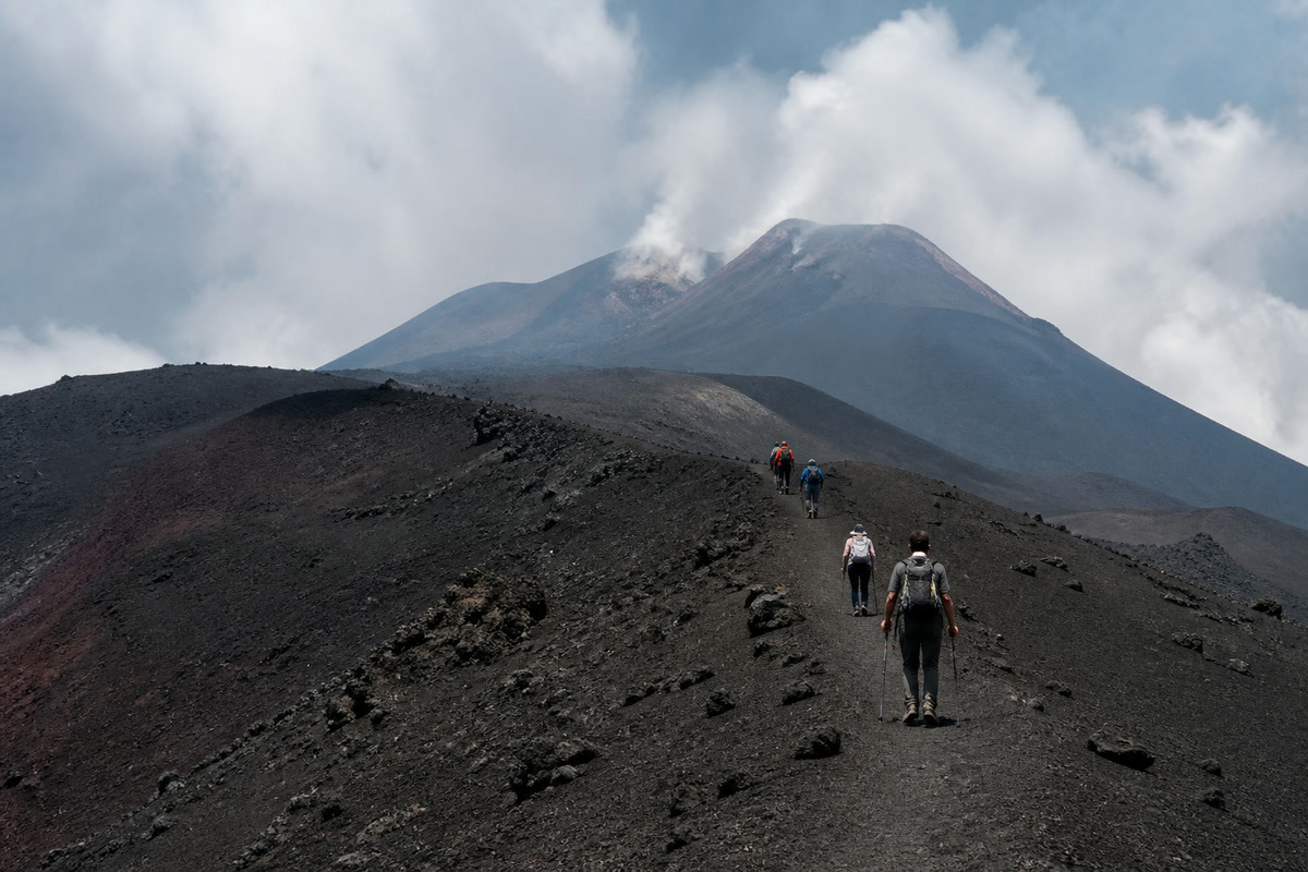 Escursionisti sul crinale con vista sui crateri sommitali fumanti