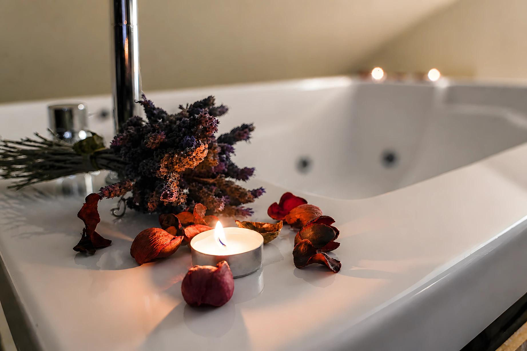 La zona spa di Tifone: il bordo della vasca idromassaggio, candela accesa e petali di rosa