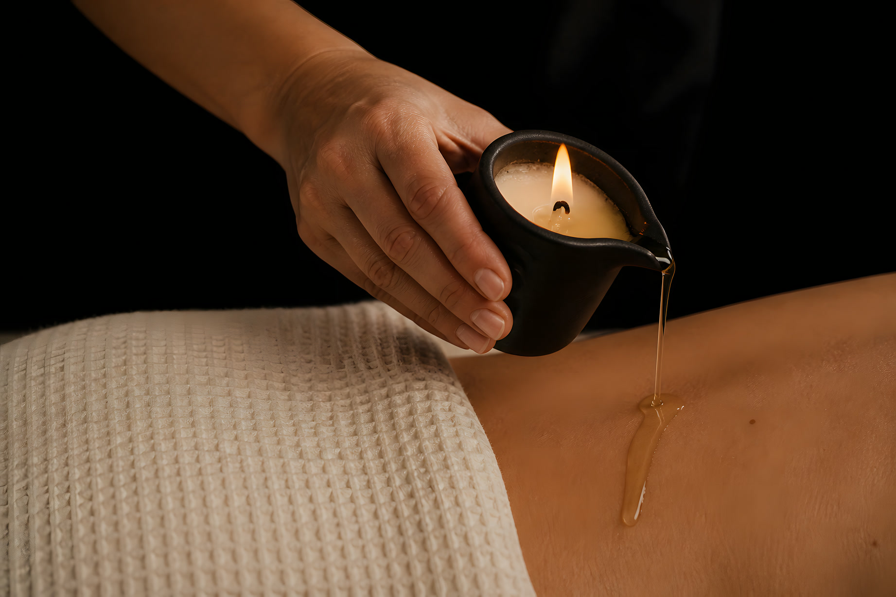 Candela da massaggio in ceramica scura che cola olio caldo sulla schiena