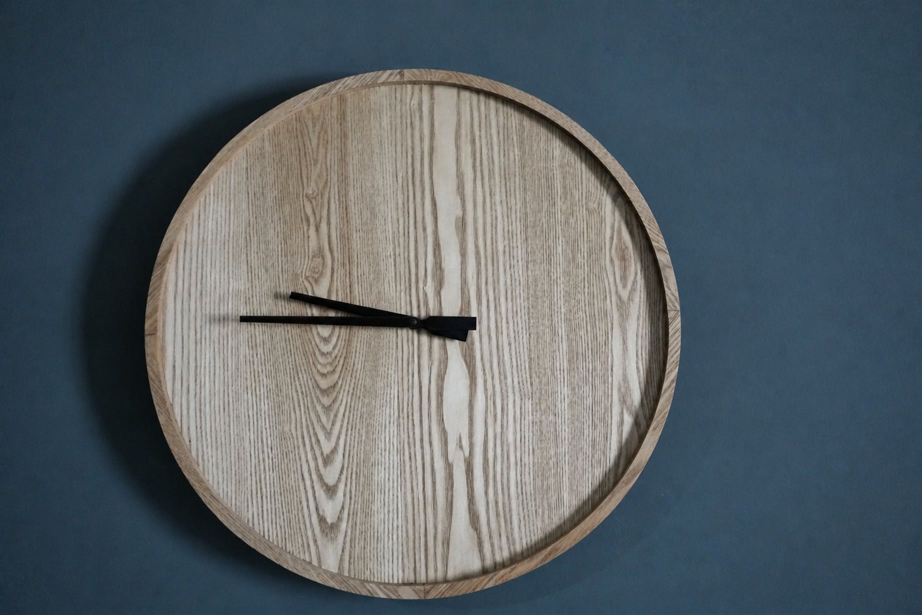 Grande orologio in legno chiaro su parete blu profondo