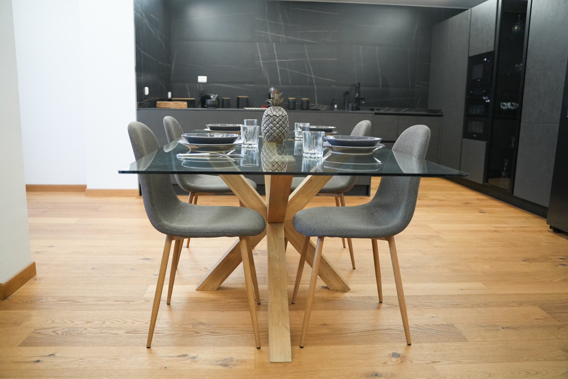Il tavolo di vetro apparecchiato nella cucina comune, piano in marmo nero