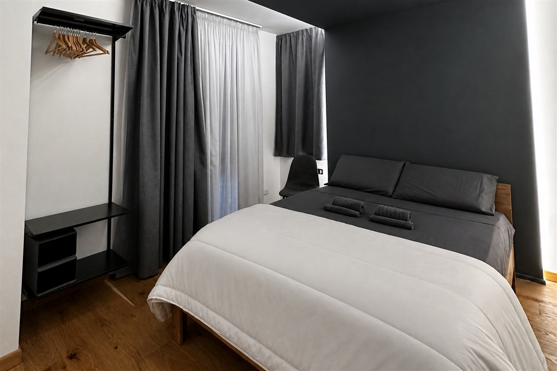 La camera di Theros & Icaro: letto matrimoniale, parete scura e luce dal soffitto