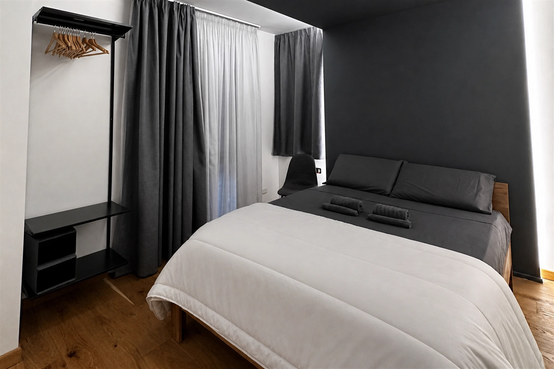 La camera di Theros & Icaro: letto matrimoniale, parete scura e luce dal soffitto