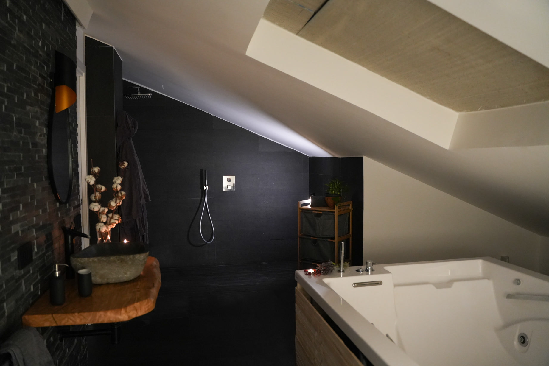 La zona spa di Tifone: parete nera, doccia e vasca idromassaggio nella luce serale