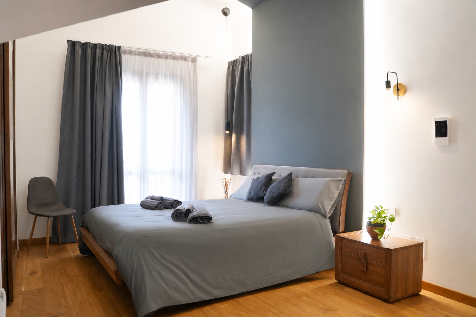 Camera di Theros & Icaro: letto con testiera imbottita, legno chiaro e luce naturale