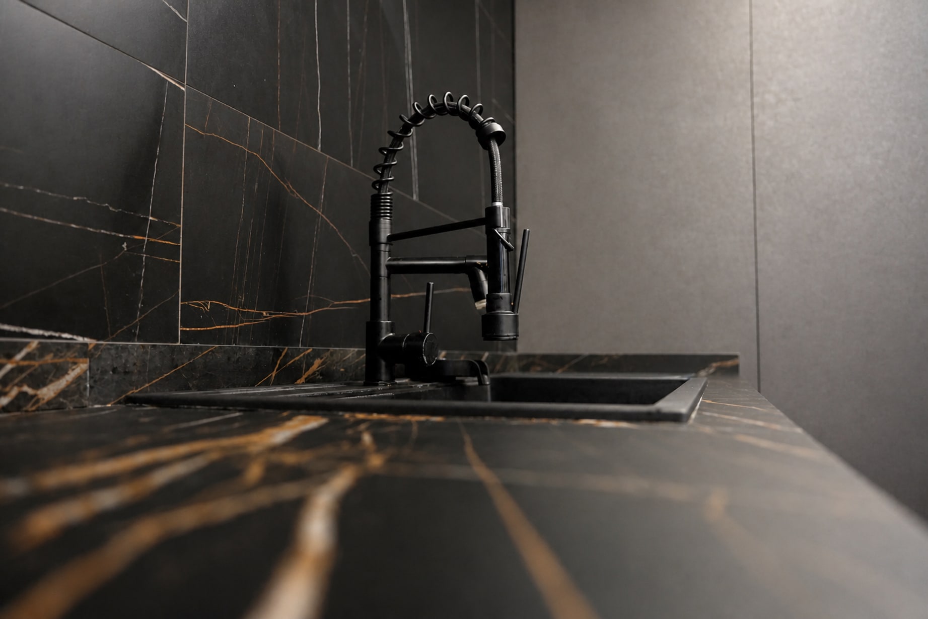 Rubinetto nero su piano cucina in marmo nero venato d'oro