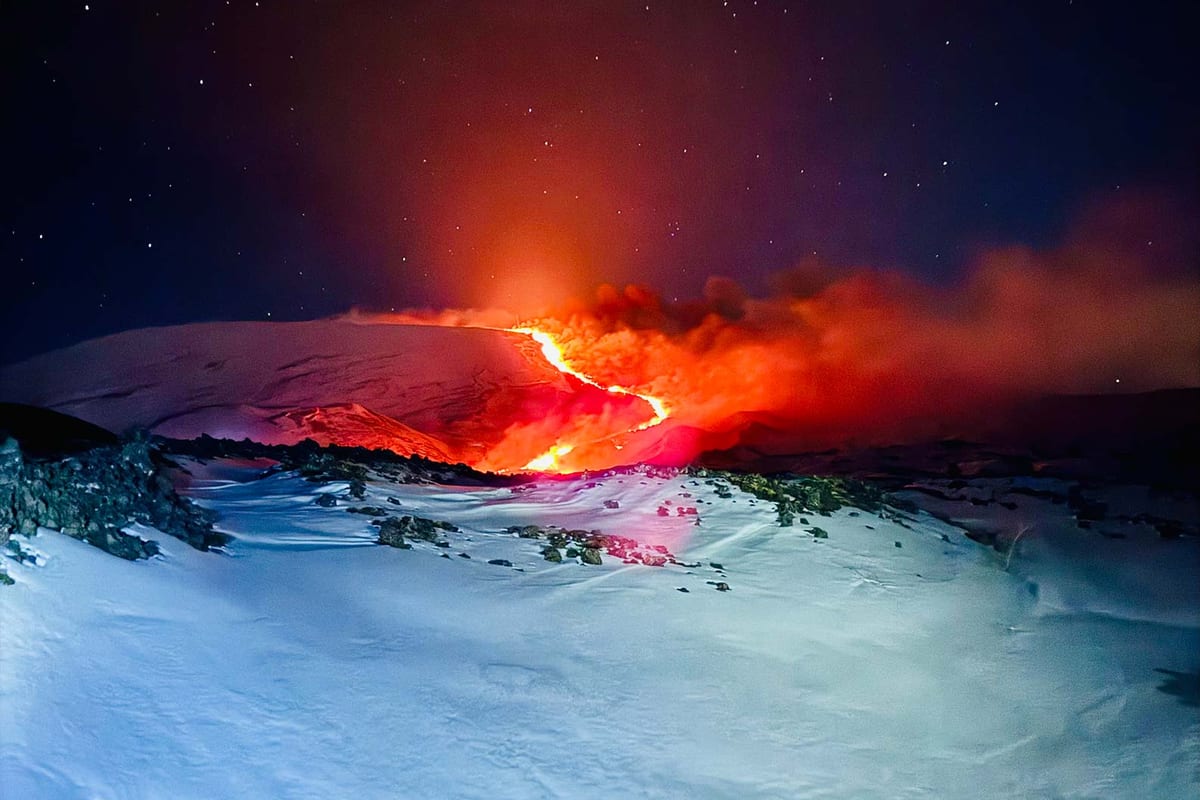 La colata incandescente che scende sulla neve, di notte
