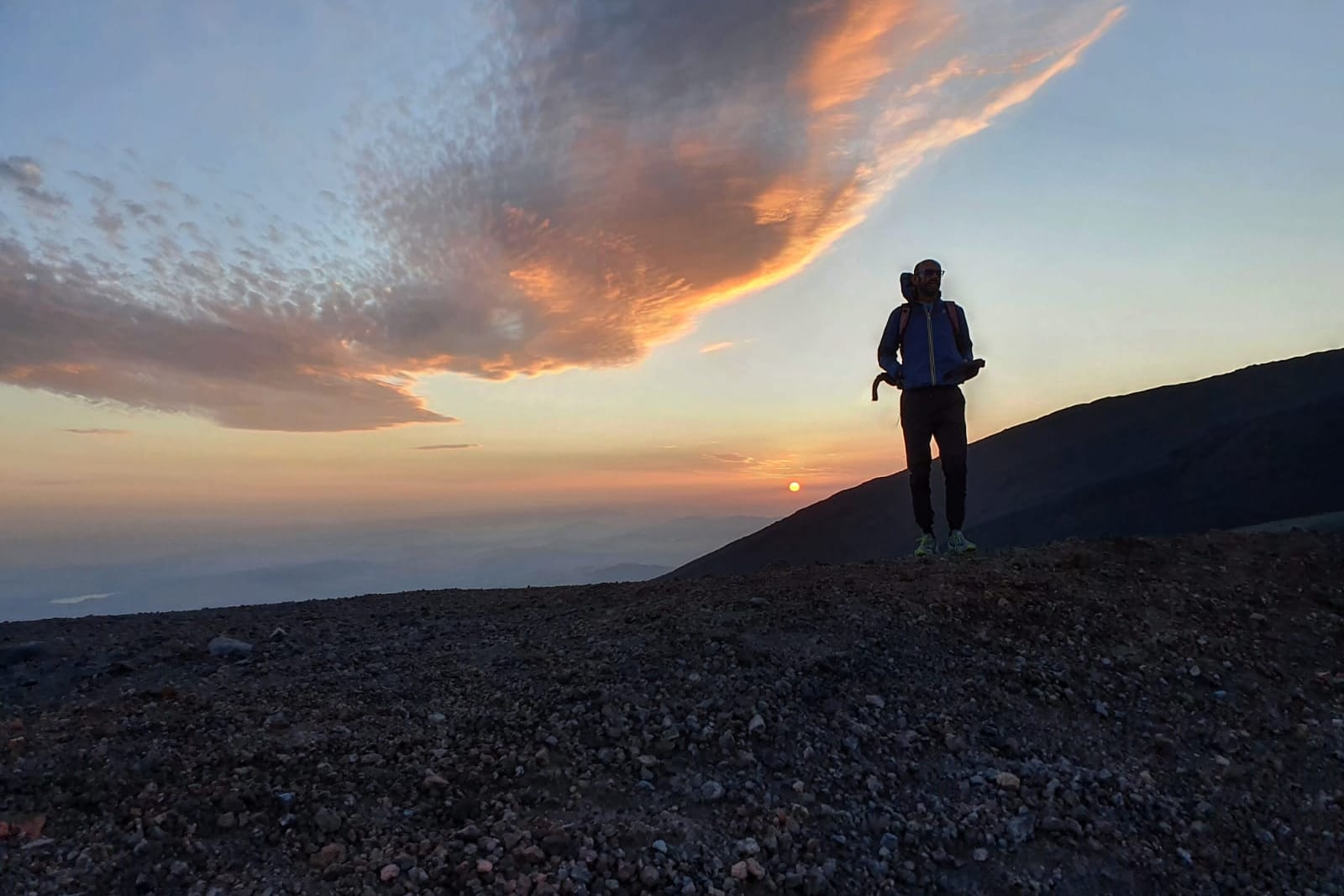 Escursionisti sul cratere al tramonto, con il vulcano alle spalle