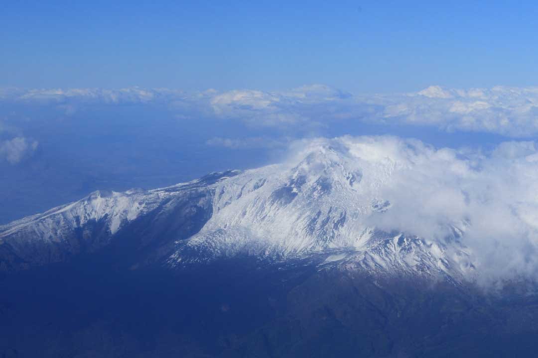L’Etna innevato visto dall’alto, in volo tra le nuvole