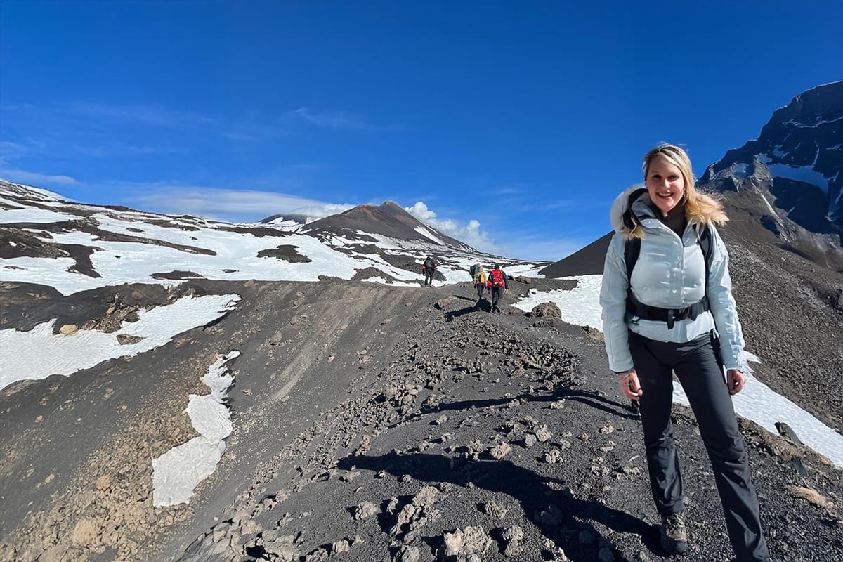 Escursionisti in cammino sul terreno vulcanico, tra le chiazze di neve
