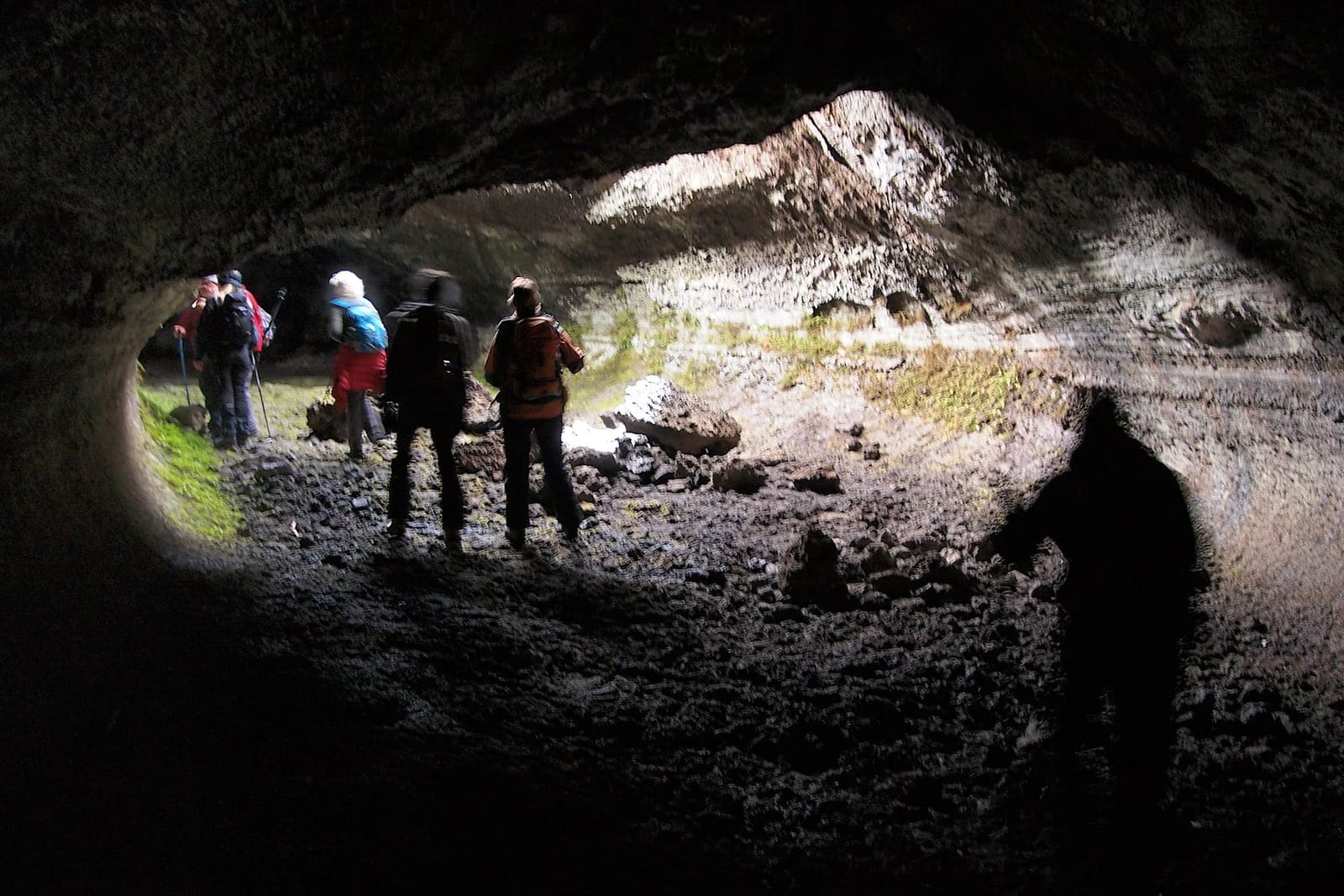 Escursionisti in controluce all’imbocco della grotta di scorrimento lavico