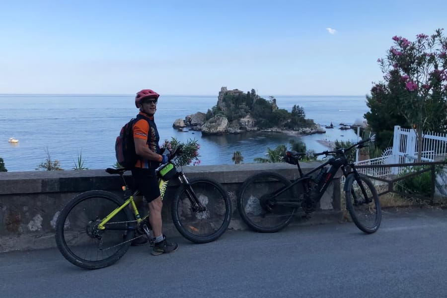 Ciclisti in discesa su sterrato con il mare sullo sfondo