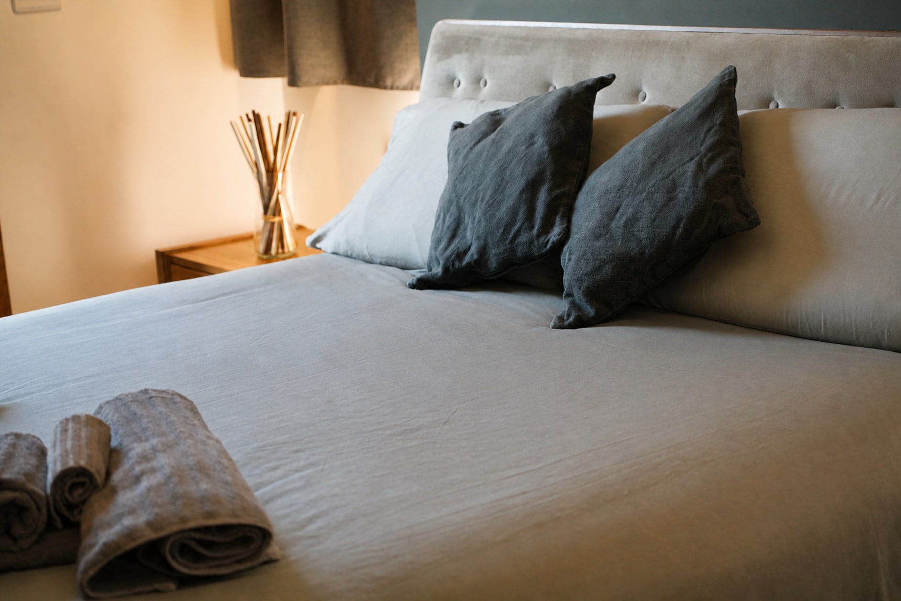 Letto rifatto con cuscini grigi nella suite Aera, luce laterale calda